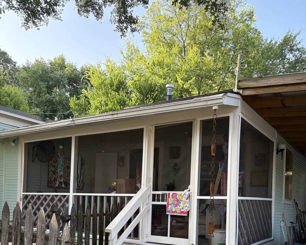 Screened front porch of the Naturally Memphis home, framed by mature trees